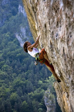 Rock climber tackles a very overhanging route on the famous limestone cliffs of the Gorge du Tarn in the Massif Central, near Millau and Rodez, south west France 