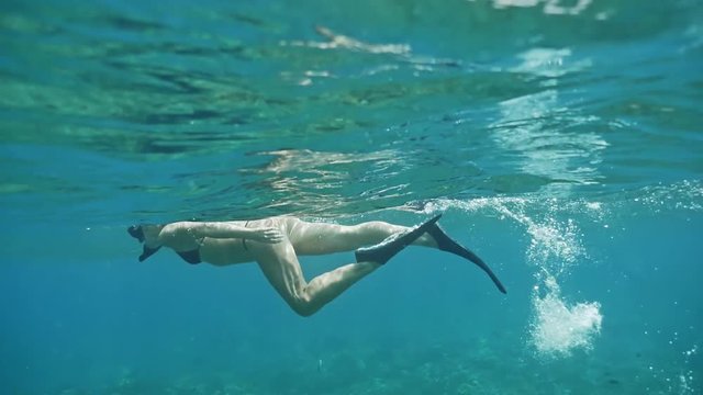 Underwater footage of a girl snorkeling in the blue ocean.