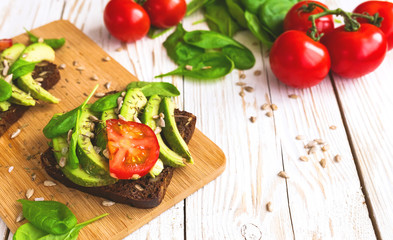Toast with sliced avocado, tomatoes, spinach and spices