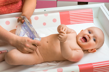 Mother changing diaper to her little baby girl © andriano_cz