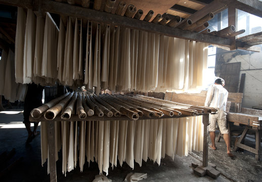 Sheets of freshly cooked rice sheets hanging on bamboo poles to be shredded into rice noodles and dried, Hsipaw, Shan state