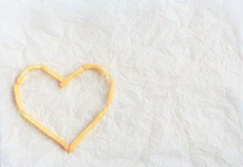 The symbols of the heart is lined with french fries on kraft pap