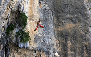 A man on a long and technically demanding face climb on the limestone cliffs of the Mascun Canyon, Rodellar, Sierra de Guara, Aragon, southern Pyrenees, Spain