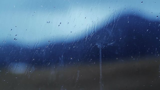 Blurred image of mountainson the background a rain spattered window glass