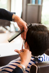 Barber cutting customer's hair with a pair of scissors