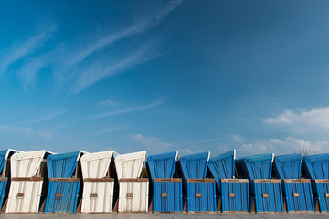 blaue und weisse Strandkörbe zum Abtransport in Winterlager vor blauem Himmel
