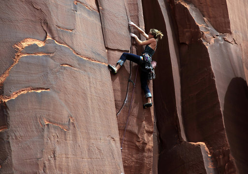 A rock climber tackles an overhanging crack in a sandstone wall on the cliffs of Indian Creek, a famous rock climbing area in Canyonlands National Park, near Moab, Utah