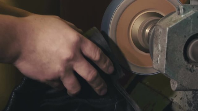 Detail on the hands of Shoemaker reparing sole of leither boots