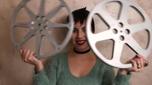 Young woman actress smiling and showing movie reels on her face