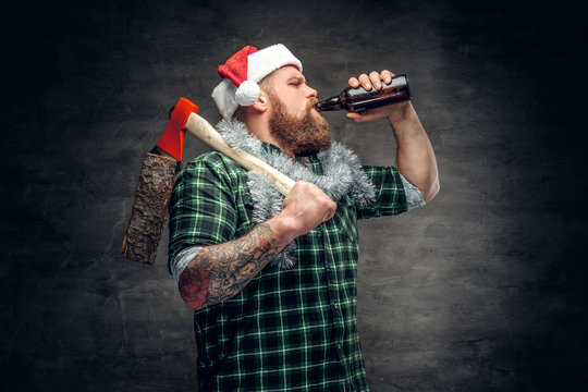 A man in Santa's hat drinking beer.