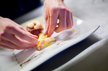Obraz na płótnie Canvas Chef preparing a dish with tuna fillet and shrimps
