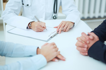 Close up of patients hands and doctor taking notes. Ward round, patient visit check, medical calculation and statistics concept. Physician ready to examine patient