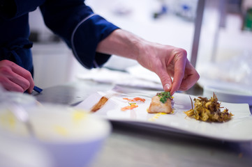 Chef preparing a cod filet with artichokes