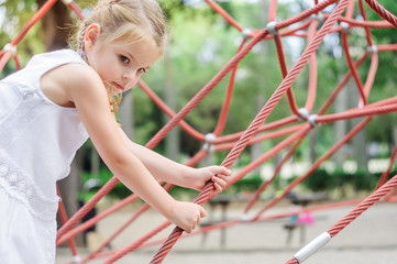 Girl playing in the park.  Little girl climbing on outdoor playg