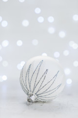 Christmas scene with one white and silver ball and christmas bokeh lights in background