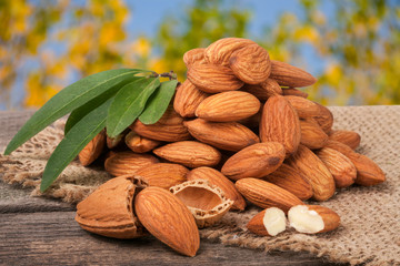 heap of peeled almonds with leaf on a wooden table blurred garden background