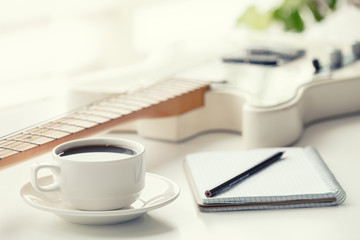 Guitar, coffee, notepad and pencil.