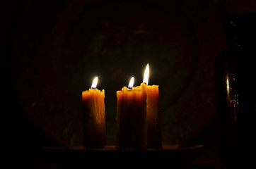 Antique candle burning in a dark room. Christmas Eve, divination, yuletide. Christmas backgrounds. holiday rituals, religion, spirituality, zen. space for text, close-up, copy space.