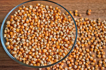 Popcorn kernels in a bowl on a wooden table