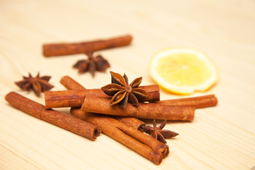 seasoning cinnamon (Cinnamomum), anise (Anisium vulgare Gaerto) and lemon lies on a light wood surface, spilled from a jar,  close-up, background, healthy lifestyle