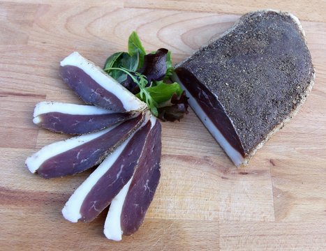 tranches de magret de canard s&eacute;ch&eacute; sur une planche en bois