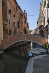 Fototapeta na wymiar Shabby Venice. Bridge across the canal against eroded facades
