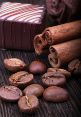 coffee beans, cinnamon sticks and chocolate on wooden background