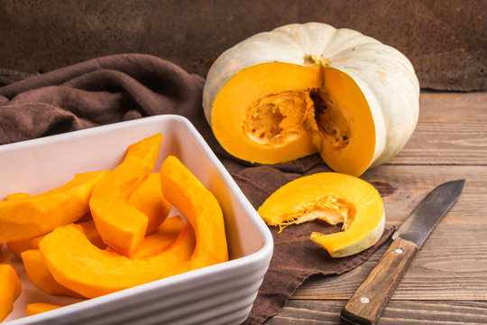 Ripe peeled pumpkin cut into slices in a white bowl for baking o