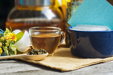 Tea in a glass cup with Dry (black and green) tea in wooden spoons, Herbal teabags on burlap tablecloths. International Tea Day december 15 