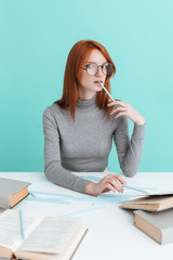 Attractive redhead young woman in round glasses sitting and reading