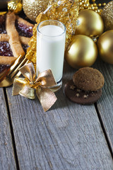 Milk and cookies for Santa Claus around gold decorations and Christmas toys 