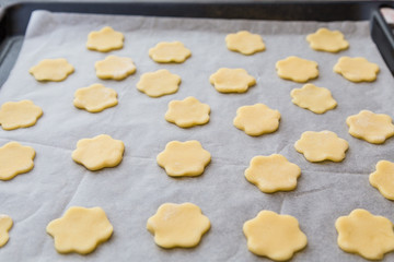 Fototapeta na wymiar Biscotti artigianali a forma di fiore stesi su teglia da forno