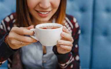 Close up lifestyle portrait of beauty brunette woman holding cup with her morning tea and drinking it