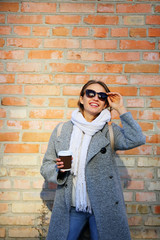 Happy girl with coffee holding sunglasses