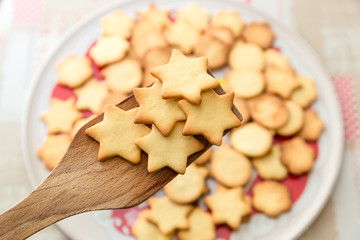 Biscotti artigianali a forma di stella appena sfornati su paletta di legno