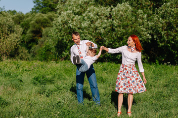 Fototapeta premium Cheerful parents walking in the park with his son