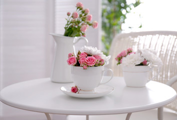 Fototapeta na wymiar Flower bouquet of rose and chrysanthemum in cup on table