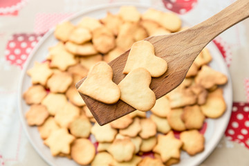 Biscotti artigianali a forma di cuore appena sfornati su paletta di legno