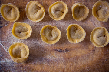 Freshly prepared Italian tortellini on wooden board