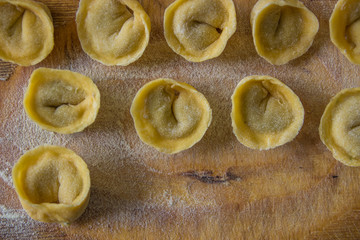 Freshly prepared Italian tortellini on wooden board top view