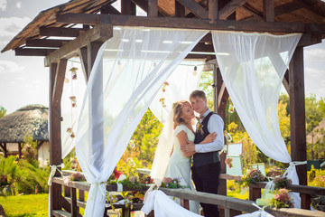 Obraz na płótnie Canvas Bride kissing groom, while her veil is fluttering
