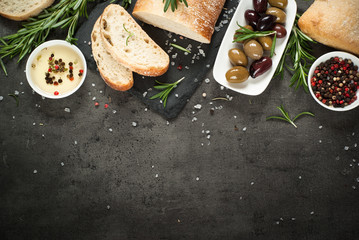 Italian ciabatta bread  on black slate with herbs and olives.
