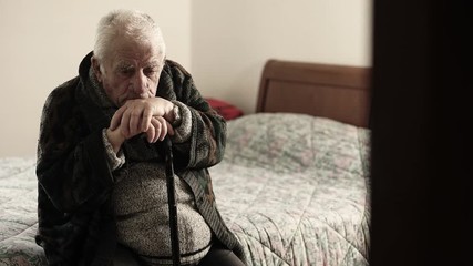 sick old man sitting on the bed in the nursing home