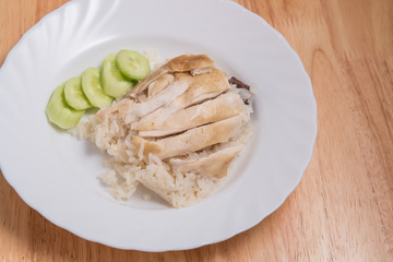Sliced Hainan-style chicken with marinated rice in white dish on wooden plate,This Thai food is called  Khao Man Kai .