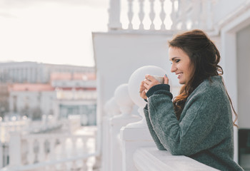 Beautiful woman relaxing and drinking coffee on the balcony in the morning