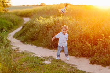 stylish little boy playing with a bunch of flowers on the road