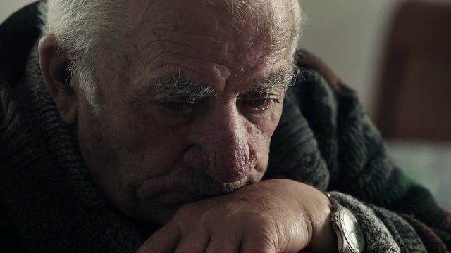 old man thinks resting his chin on his cane