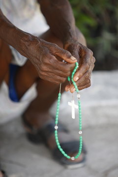 Haitian woman praying with prayer beads, Port au Prince, Haiti
