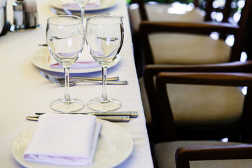 Empty glassware stands between dinner plates