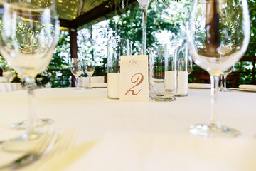 Beige card with number 2 stands on white dinner table